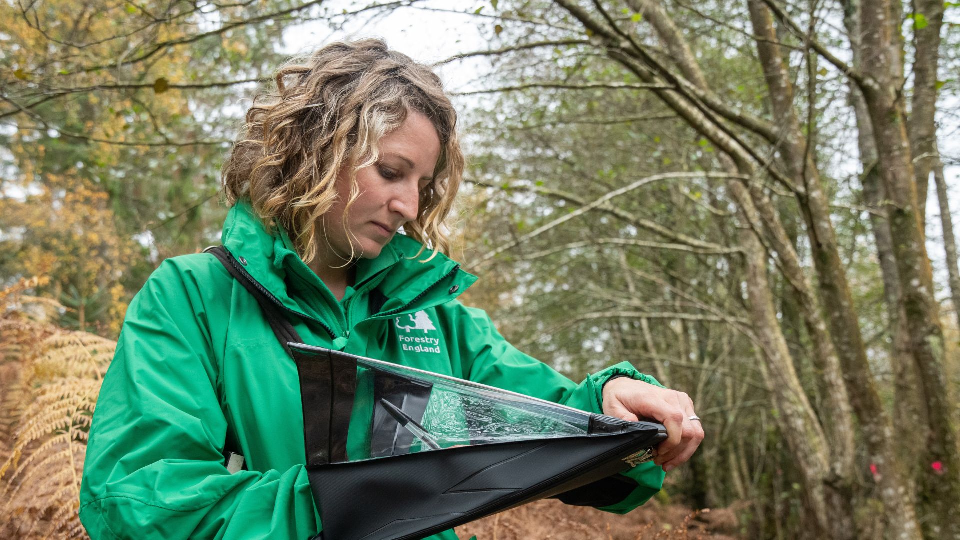 A woman in a green top looking at a clipboard